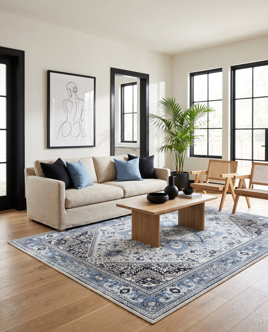 Darya Sky & Ink rug in a modern coastal living room with a linen sofa and cane chairs