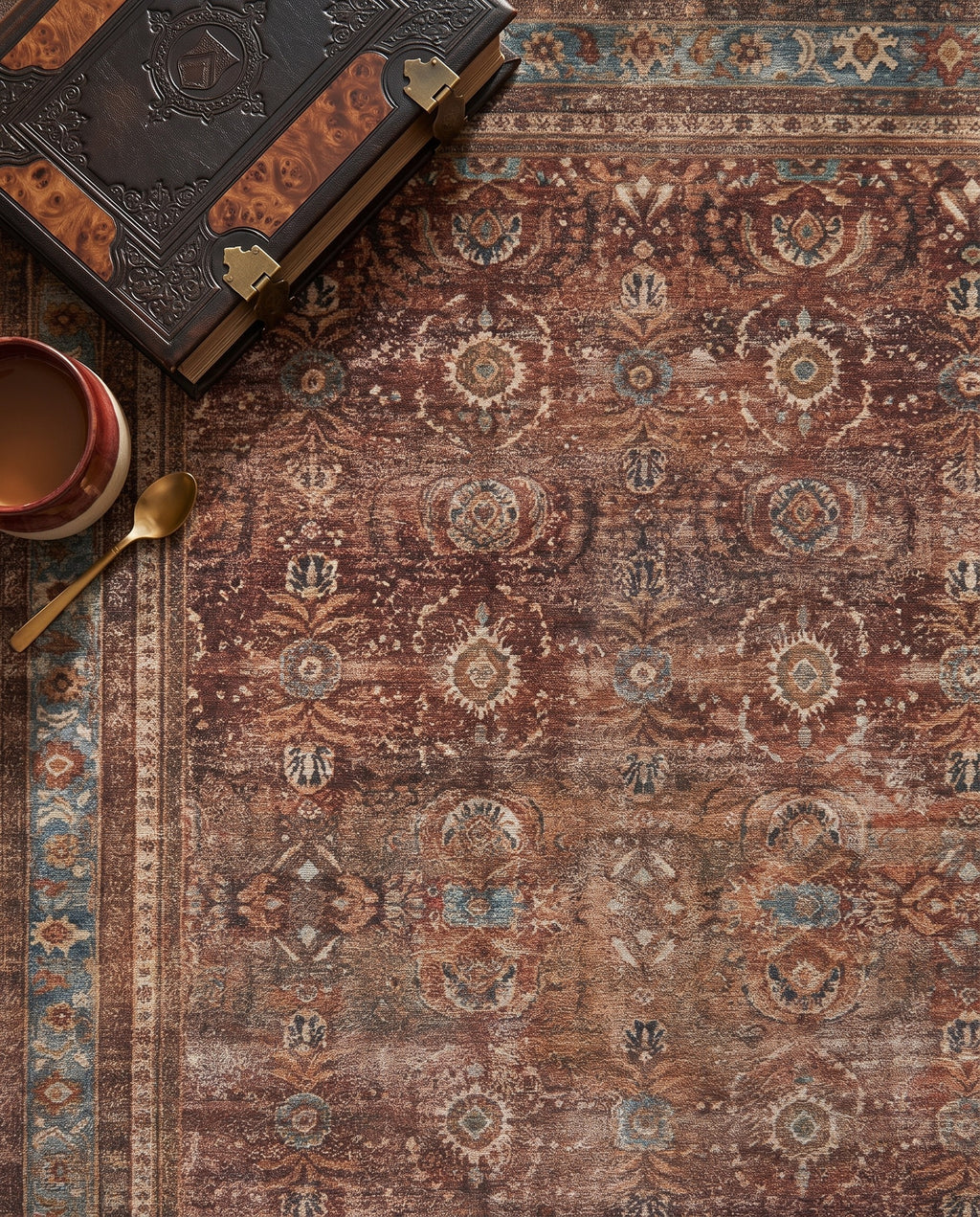Close-up of the Kahroba rug walnut field and faded teal border, soft low-pile velvet