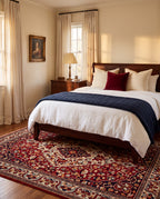 Laleh Garnet & Cream rug under a wood bed with navy and white linen