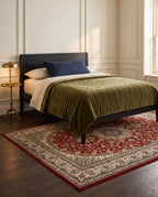 Shahrzad Crimson & Navy rug under an ebonized bed with an olive velvet quilt