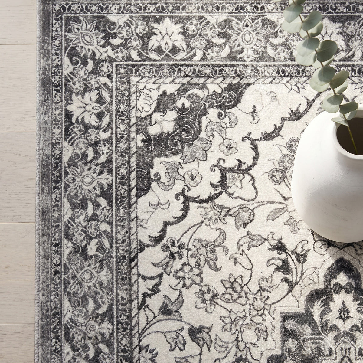Simin rug corner with a white plaster vase and eucalyptus