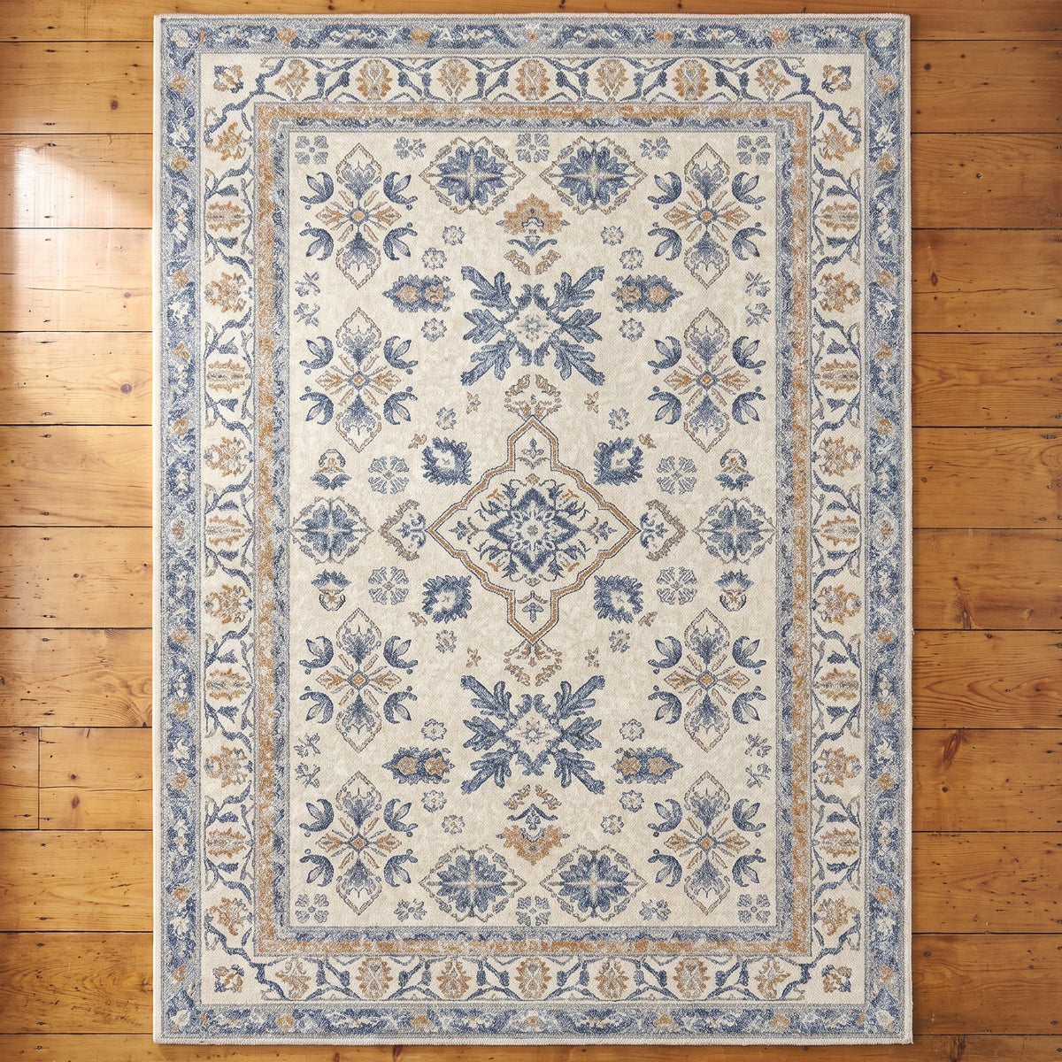 Yasaman Ivory & Cornflower rug seen from above on an antique pine floor