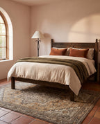 Zarin Ochre & Umber rug under a carved oak bed in a Mediterranean bedroom